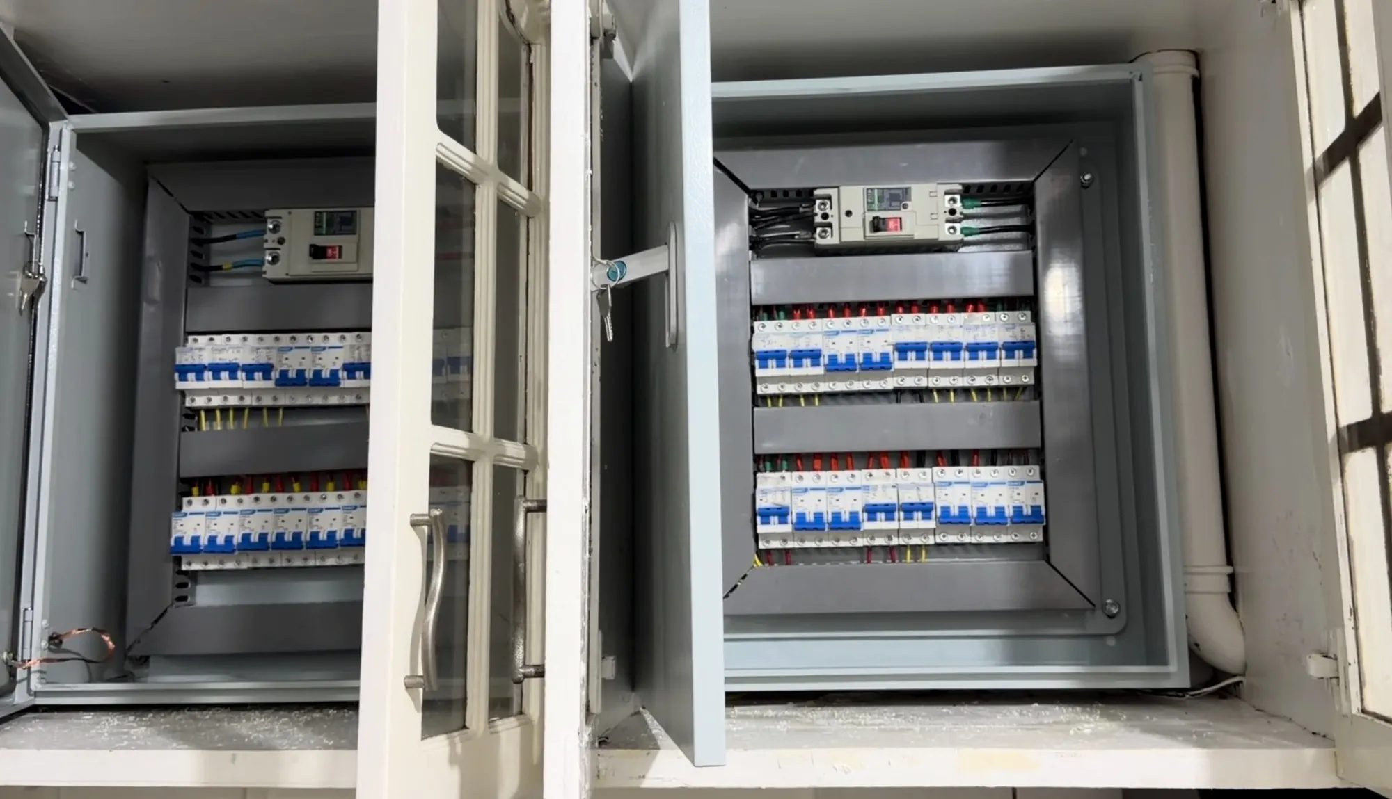 Two open breaker enclosures side by side, every circuit breaker in neat labelled rows with the wiring dressed behind.